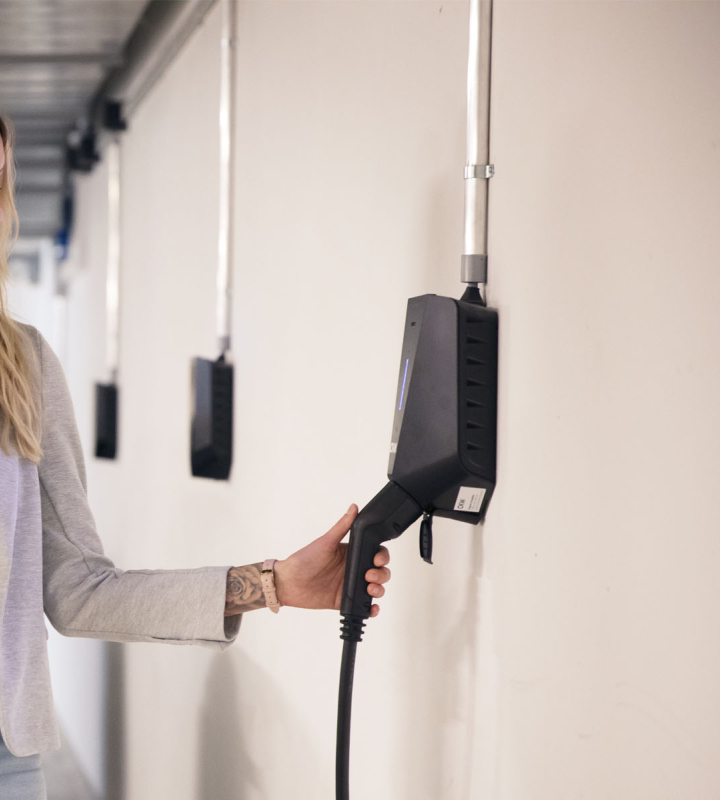 Une femme recharge sa voiture électrique dans un garage sous-terrain