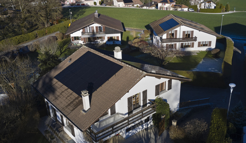 Luftaufnahme von Häusern mit Solarmodulen auf den Dächern, die das Engagement von Groupe E für nachhaltige Solarlösungen für Privatkunden hervorheben