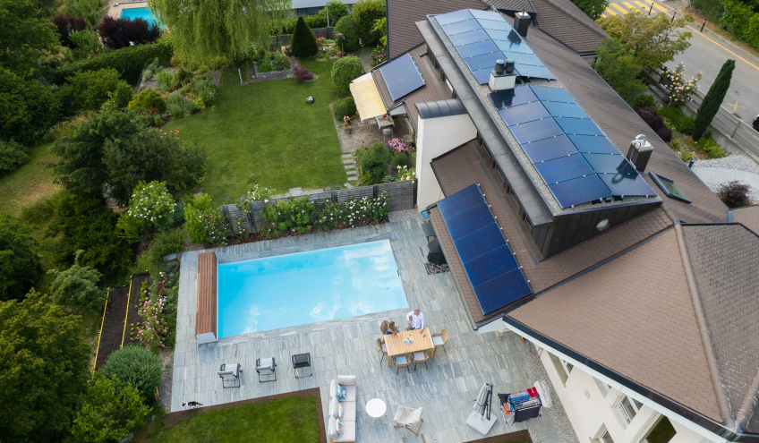 Luftaufnahme eines Hauses mit Solarpanels, das das nachhaltige Engagement von Groupe E für sein Stromprodukt Vario für Privatkunden symbolisiert