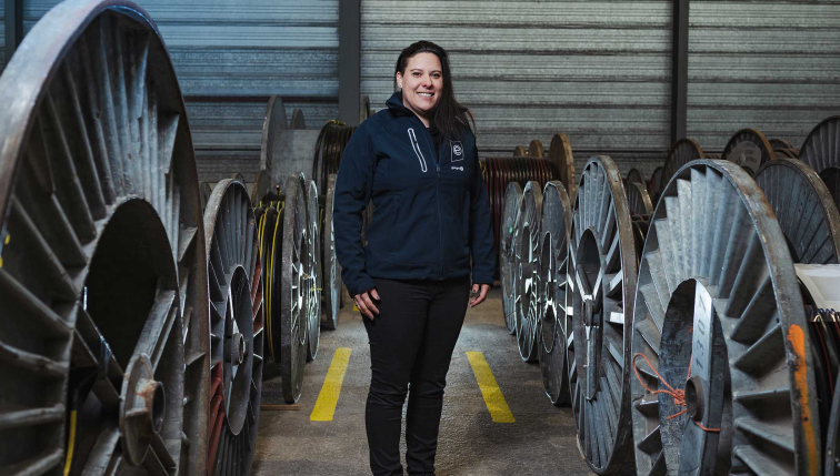 Une collaboratrice de Groupe E posant dans un dépôt de bobines électriques