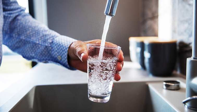 un homme remplit un verre d'eau à son robinet