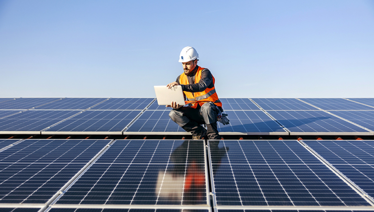 Un technicien effectue de la maintenance de panneaux solaires sur un toit. 