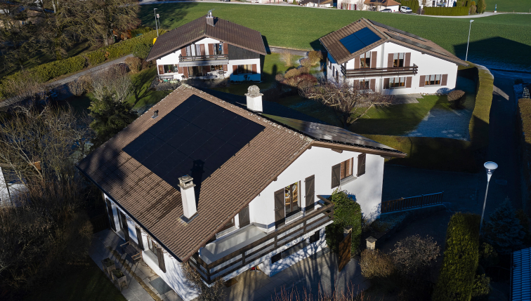 Vue aérienne d'un quartier, dont les maisons sont équipées de panneaux solaires installés par Groupe E