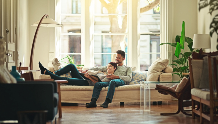 Un couple profite d’un moment de détente dans un salon lumineux et chaleureux, symbolisant le confort offert par le gaz naturel, une solution énergétique proposée par Groupe E pour les particuliers