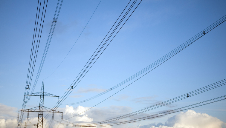 Photo d'une ligne à haute tension, sur fond de ciel bleu