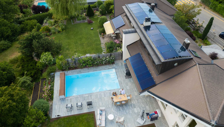 Vue aérienne d'une maison équipée de panneaux solaires, symbolisant l'engagement durable de Groupe E pour son produit électricité Vario destiné aux clients privés