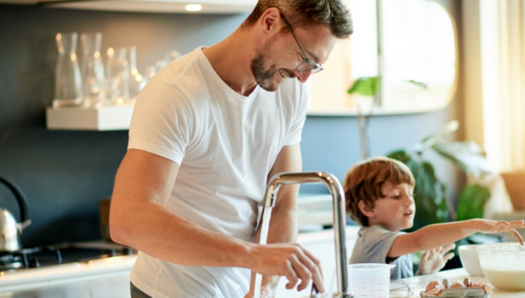 Ein Vater und sein Sohn in der Küche, die sich die Hände heiß waschen