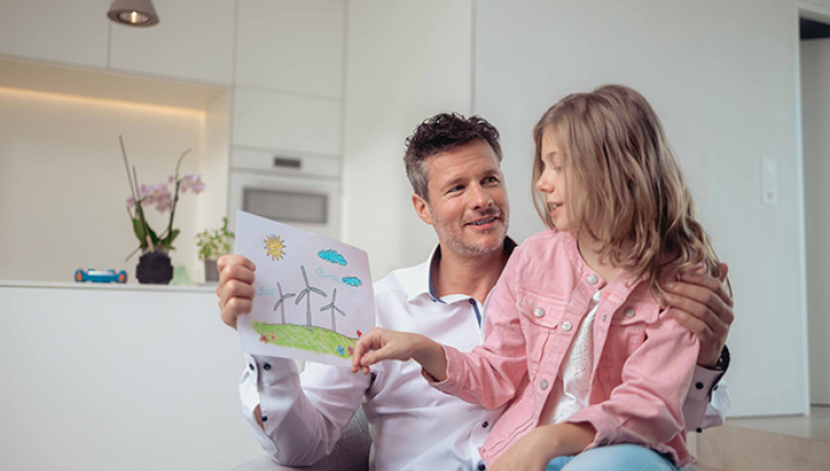Ein Vater und seine Tochter betrachten eine Zeichnung einer Windkraftanlage.