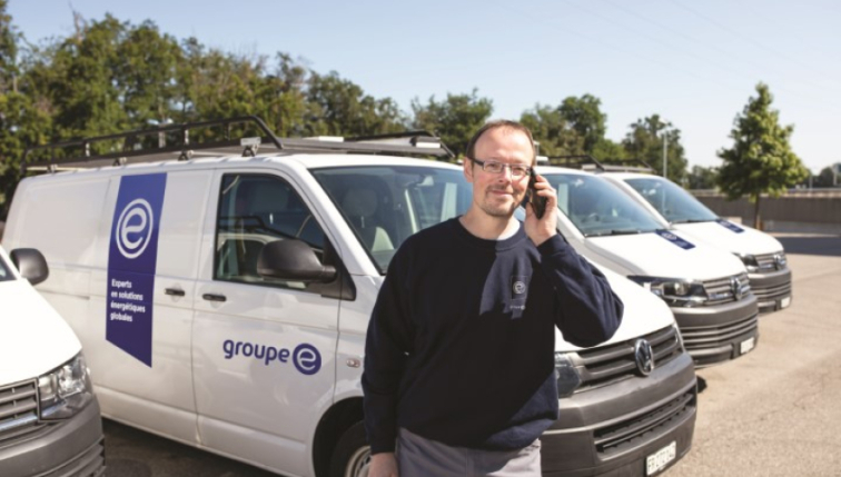 Ein Techniker am Telefon vor einem Groupe E-Kleintransporter