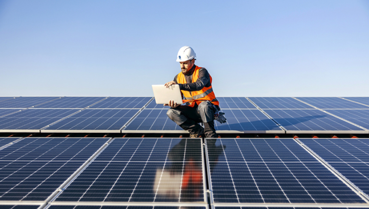 Un ouvrier sur une installation de panneaux solaire lisant ces documents