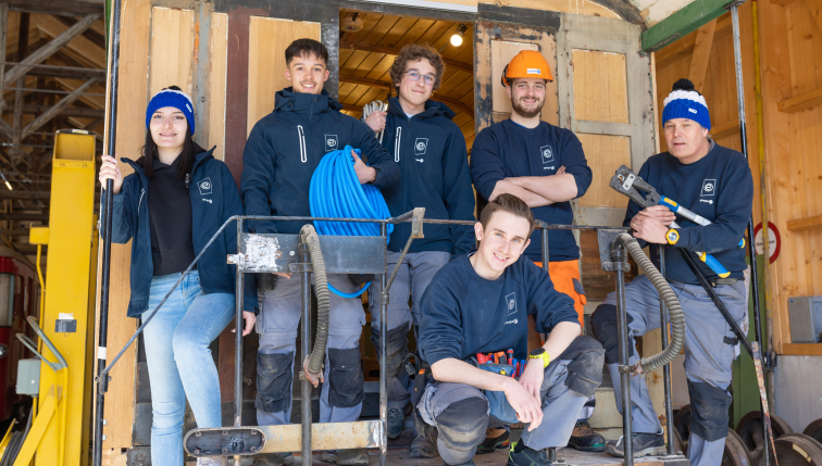 Des apprentis de Groupe E posant devant un wagon GFM qu'ils sont en train de rénover