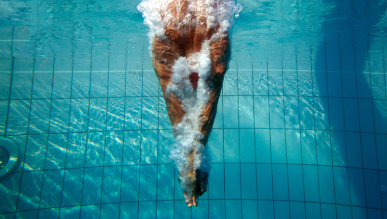 ein Schwimmer in einen von Groupe E behandelten Pool springt