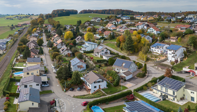 Luftaufnahme eines Dorfes mit Photovoltaikanlagen