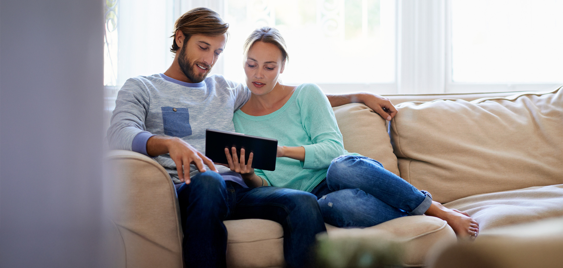 Un couple regardant sa consommation électrique, installé sur son canapé