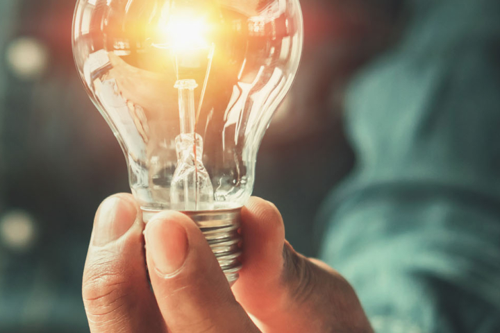 Une main d'homme tient une ampoule allumée