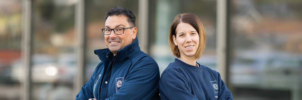 Deux collaborateurs de Groupe E posent devan un bâtiment de l'entreprise.