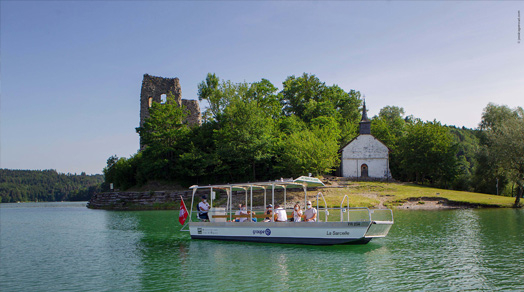 Ein Elektroboot mit Solarpaneelen fährt vor der Île d’Ogoz.